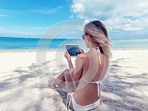 summer holidays, vacation, technology and internet - girl looking at tablet pc on the beach chair