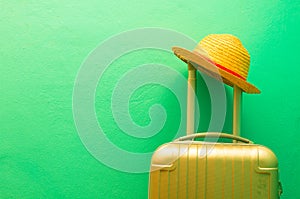 Summer holidays, vacation and travel concept. Suitcase or luggage bag with sun hat on green background