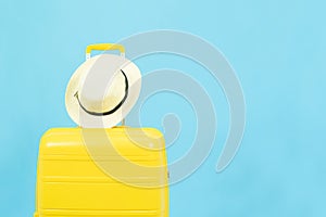 Summer holidays, vacation and travel concept.Yellow Suitcase or luggage bag and sun hat isolated on blue background with copy