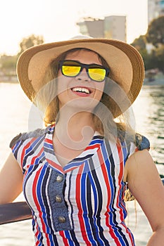 Summer holidays, vacation, travel and people concept - smiling young woman wearing sunglasses and hat on beach over sea