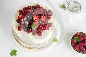 Summer home biscuit cake with curd cream, decorated with fresh berries of strawberries, raspberries and currants.