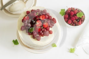 Summer home biscuit cake with curd cream, decorated with fresh berries of strawberries, raspberries and currants.