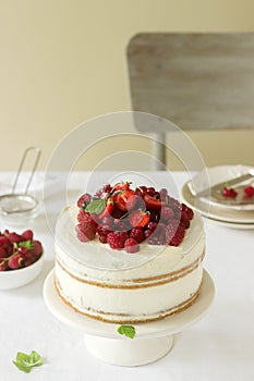 Summer home biscuit cake with curd cream, decorated with fresh berries of strawberries, raspberries and currants.