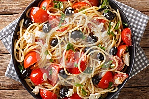 Summer homemade greek pasta salad with cheese, olives, tomatoes close-up on a plate. Horizontal top view