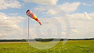 Summer hot day on sport airport with abandoned windsock, wind is blowing