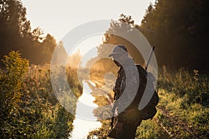 Summer hunting at sunrise. Hunter moving With Shotgun and Looking For Prey.