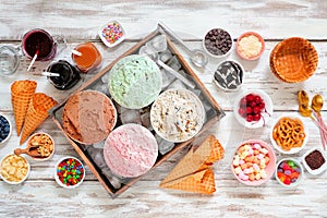 Summer ice cream bar top view table scene on a rustic white wood background