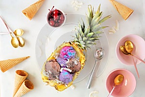 Summer ice cream in a pineapple. Table scene on white marble.