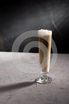 Summer iced coffee frappuccino frappe or latte in tall glass on concrete table on black background