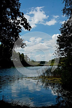 Summer idyllic landscape with a lake under a blue sky on a warm sunny day