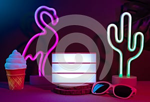 Summer items with flamingo, cactus, sunglasses and blank light box with neon pink and blue light on table with monstera leaf.Mock