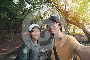 Summer journey vacations concept, Asian man and woman traveler with backpack standing take photo selfie near tropical forest