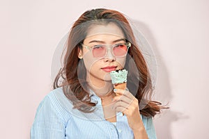 Summer, junk food and people concept - young woman or teenage girl in sunglasses eating ice cream