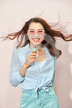 Summer, junk food and people concept - young woman or teenage girl in sunglasses eating ice cream
