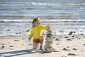 Summer kid meditation. Child with zen stones on sea beach, meditation, spa and harmony. Calm balance concept. Kids play