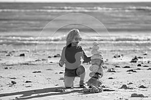 Summer kid meditation. Kid boy with zen stones on sea beach, meditation, spa and harmony. Calm balance concept. Kids