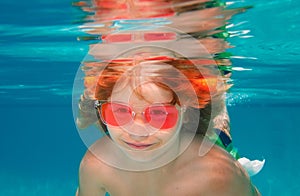 Summer kids face. Young boy swim and dive underwater. Under water portrait in swim pool. Child boy diving into a