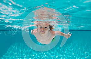 Summer kids in water in pool underwater. Kid boy swimming underwater on the beach on sea in summer. Blue ocean water