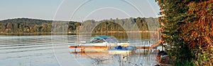 Summer on lake cottage. Small yacht boat by wooden dock pier on lake at sunset. Canadian Ontario Muskoka countryside travel
