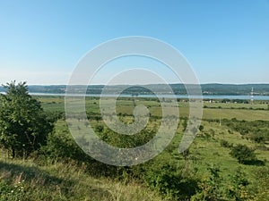 Summer landscape with agricultural field near the village on the lake