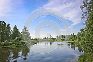 Summer landscape - calm flat river flows among forests