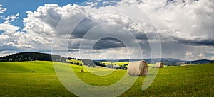 summer landscape with a field with hay bales and blue sky with white clouds