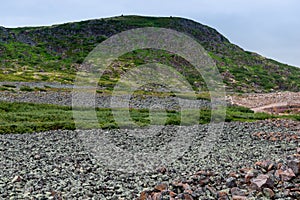 Summer landscape of green polar tundra with boulders in the foreground. Northern nature in the vicinity of Teriberka