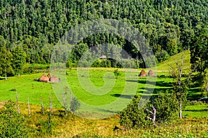 Summer landscape with haystacks in the mountains