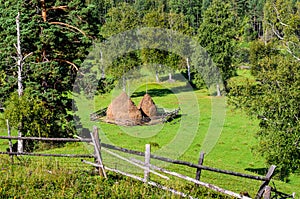 Summer landscape with haystacks in the mountains