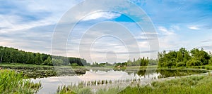 Summer landscape. Lake, forest and blue sky with beautiful clouds.