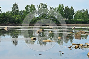 Summer landscape. Large rocks jut out of the water. The water level in the river decreased.