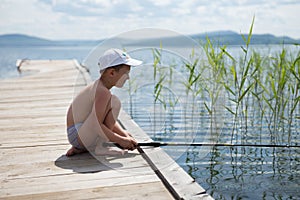 A little boy is fishing on the big lake.