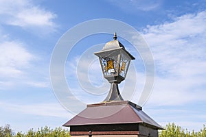 Summer landscape with old lonely street lamp and blue cloudy summer sky.