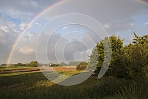 Summer landscape with rainbow, sky and corn fields. Pan