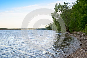 Summer landscape with a river and a rocky Bank with trees