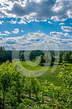 Summer landscape with sky and white curly clouds and green glade