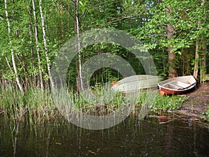 Summer landscape. two boats on the lake. one of them is upside down. trees are green. day. horizontal. copyspace