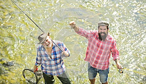 Summer leisure. Fishermen fishing equipment. Hobby sport activity. Fishermen friends stand in river. Fish normally