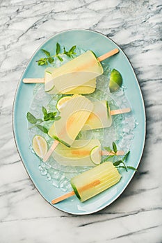 Summer lemonade popsicles with lime, mint leaves and chipped ice