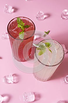 Summer lemonades with ice and mint in glass glasses top view on pink background