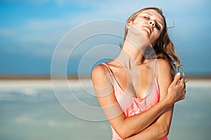 Summer lifestyle fashion portrait of young stunning blonde woman. Sunbathing, enjoying life. Wearing stylish pink swimsuit. Young