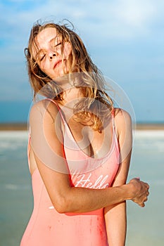 Summer lifestyle fashion portrait of young stunning blonde woman. Sunbathing, enjoying life. Wearing stylish pink swimsuit. Young