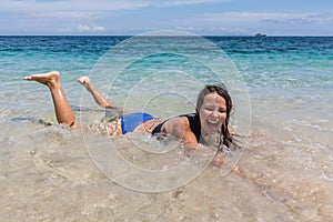 Summer lifestyle portrait of happy pretty young woman with tanned body. Enjoying life and lying in the clear sea