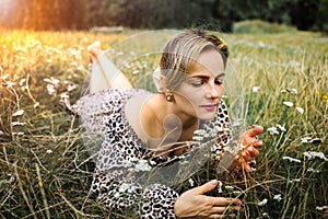 Summer lifestyle portrait middle aged woman lying on the grass outdoor. spends time in nature in summer.