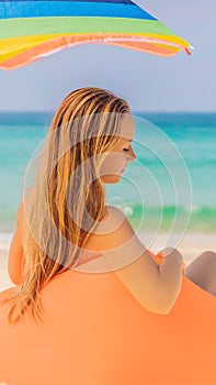 Summer lifestyle portrait of pretty girl sitting on the orange inflatable sofa on the beach of tropical island. Relaxing