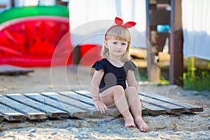 Summer lifestyle portrait of pretty girl swimming posing on the back on the inflatable watermelon in the ocean, wearing stylish