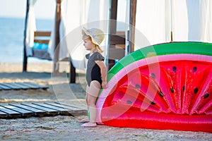 Summer lifestyle portrait of pretty girl swimming posing on the back on the inflatable watermelon in the ocean, wearing stylish