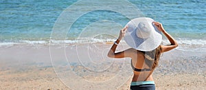 Summer lifestyle portrait of pretty young suntanned woman in big white hat. Looking at the sea. Enjoying life on beach, time to