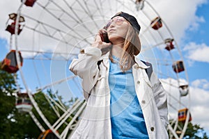 Summer lifestyle portrait woman enjoy nice day, talking smartphone. Happy female in front of ferris wheel. Young girl