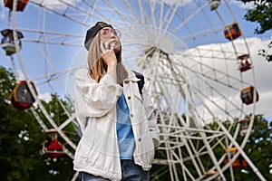 Summer lifestyle portrait woman enjoy nice day, talking smartphone. Happy female in front of ferris wheel. Young girl